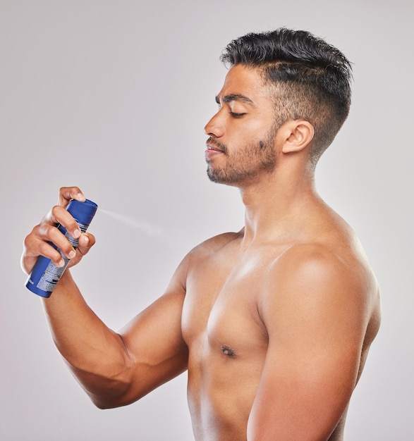 Man muss alle Blickwinkel einnehmen Aufnahme eines jungen Mannes, der Deodorant vor einem grauen Hintergrund aufträgt