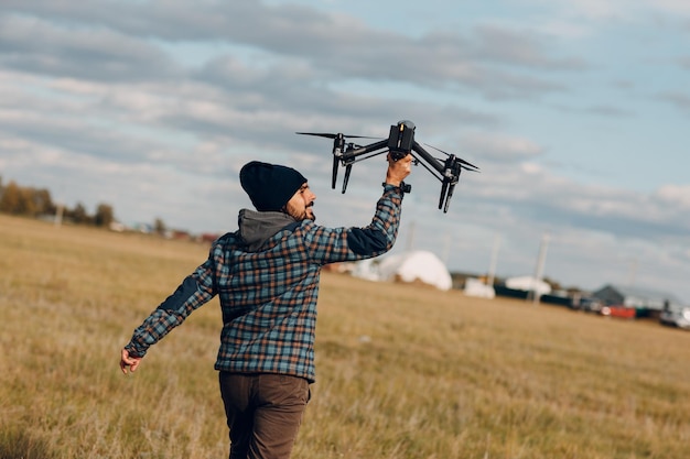 Man Pilot hält Quadcopter-Drohne in den Händen auf dem Außenfeld