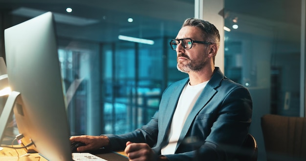 Man programmer and glasses on computer at night for programming website software update or deadline Mature person online and it with research for problem solving system error and upgrade process