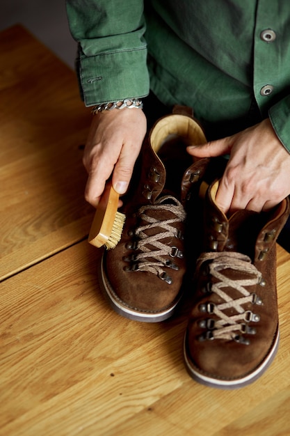 Man's Hand, die Wildlederschuhe mit einer Bürste auf Holzboden reinigt