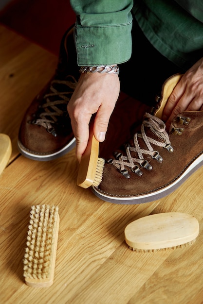 Foto man's hand, die wildlederschuhe mit einer bürste auf holzboden reinigt