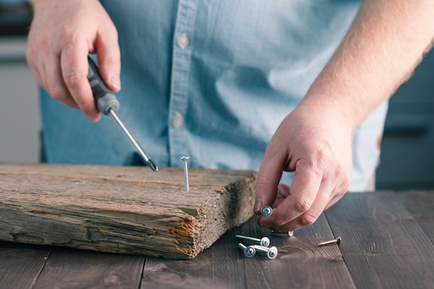 Man's Hand mit Schraubendreher Montage Holzbrett