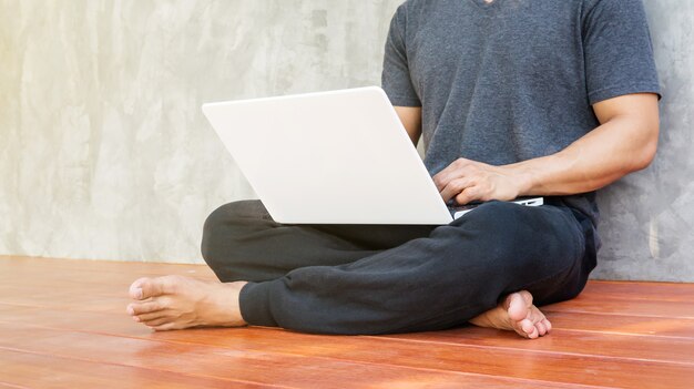 Man sitzt und benutzt einen weißen Laptop.