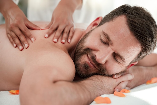 Man Spa und Rückenmassage oder Entspannung Wellness in Ruhe Gesundheits- oder Luxushotel in Selbstversorgung Muskelverspannungen oder Stress Masseuse Hände auf glücklichen Mann auf dem Tischbett im Zen verwöhnen von Physiotherapie