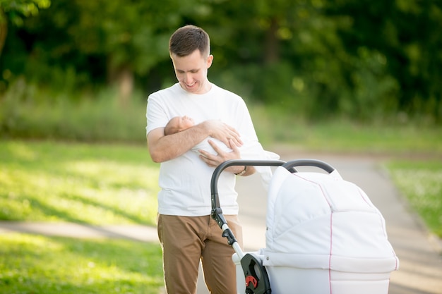 Foto man steht mit einem baby in ihren armen in den park