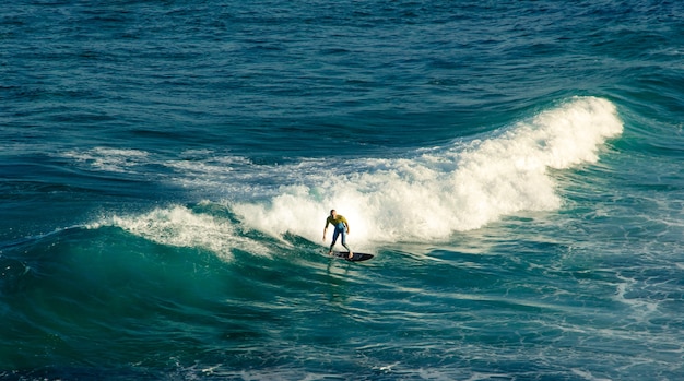 Man Surfer montado en su tabla de surf sobre las olas en verano