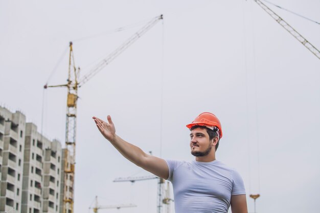 Man the builder arbeitet als vorarbeiter im helm, um die sicherheit auf der baustelle zu gewährleisten. arbeiter, ingenieur, vorarbeiter, architekt.