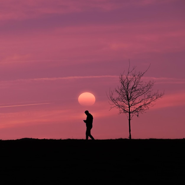 Man trekking auf dem land mit einem wunderschönen sonnenuntergang im hintergrund