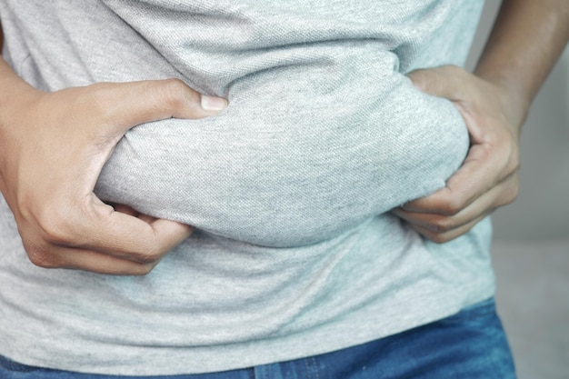 Man39s mão segurando o conceito de excesso de peso de gordura da barriga excessiva