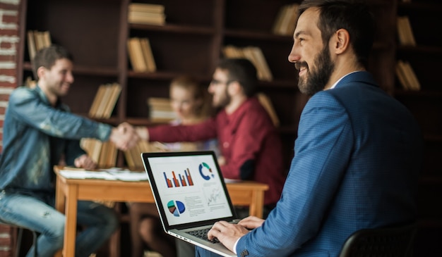 Manager Finance arbeitet mit den Marketinggrafiken auf dem Laptop im Büro