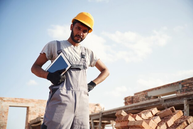 Manager mit digitalem Tablet Ein hübscher indischer Mann ist auf der Baustelle