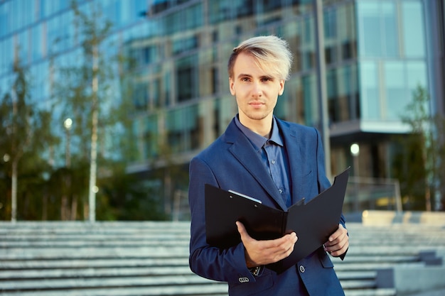 Manager mit Ordner für Papiere steht in der Nähe des Bürogebäudes