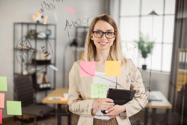 Managerin mit Tablet lächelt während der Arbeit in die Kamera