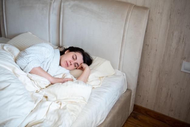 Mañana en la cama mujer despertando acostada en la cama con sábanas blancas