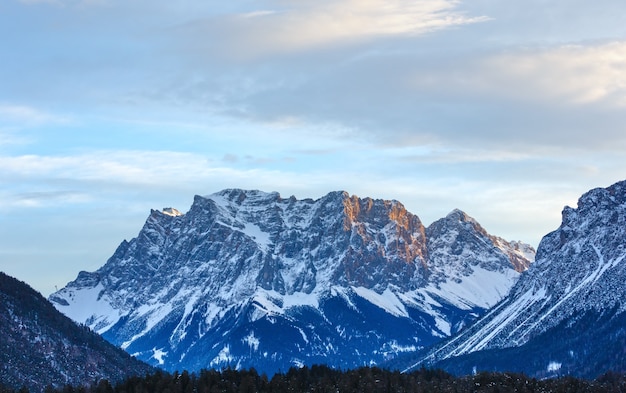 Mañana cielo nublado y pico de roca de invierno con bosque en pendiente Austria.