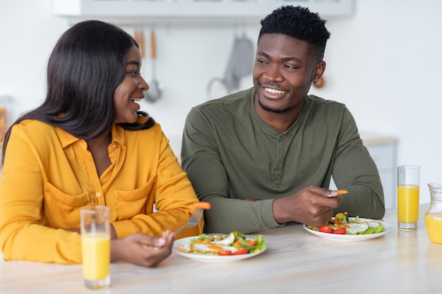 Mañana doméstica felices esposos milenarios negros desayunando en la cocina