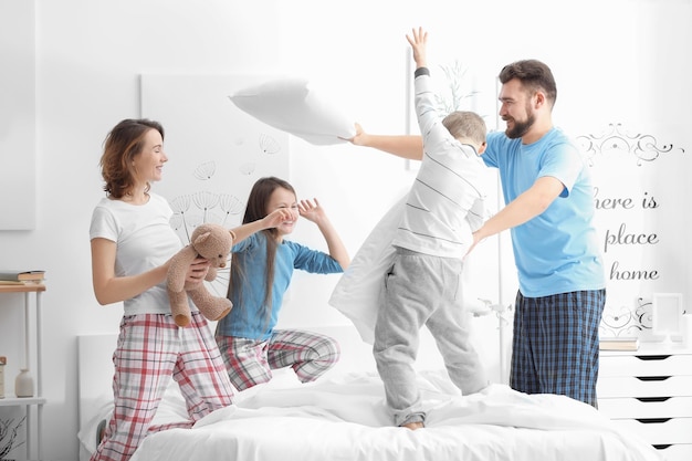 Foto mañana de familia feliz divirtiéndose en el dormitorio