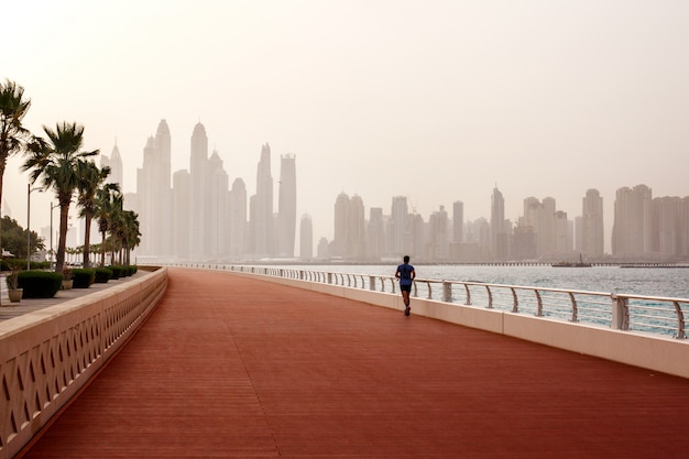 Por la mañana, un hombre corre por la carretera con una hermosa vista de Dubai.