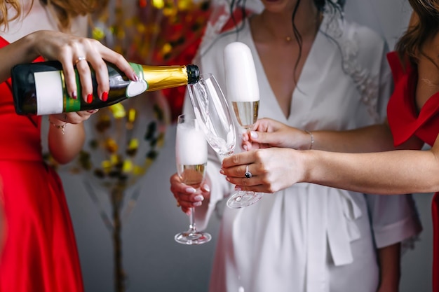 La mañana de la novia Hermosa novia con las mejores damas de honor sostiene copas y bebe champán en una habitación de hotel Detalles de la mañana de la boda