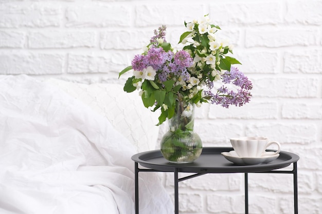 Mañana de primavera en la acogedora mesa de café del dormitorio con un ramo de diferentes flores taza de café blanco