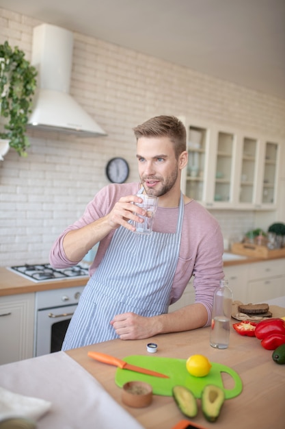 Mañana saludable. Un joven bebiendo agua en su cocina.