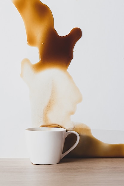 Mancha de café negro derramado de una taza blanca