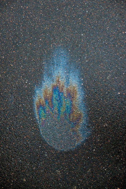 Mancha iridiscente de gasolina Gasolina en el asfalto Un gran charco de agua contaminada Un arcoíris manchado de gasolina