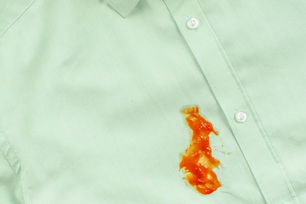 Mancha de ketchup sucia en una camisa verde concepto de mancha de vida diaria Foto de alta calidad