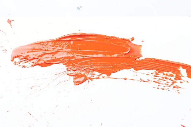Mancha de pintura acrílica mancha de pincelada caótica que fluye sobre fondo de papel blanco Fondo de color naranja creativo arte fluido
