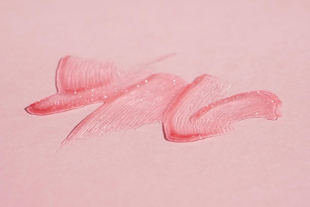 Manchas de brilho labial transparente em um fundo rosa