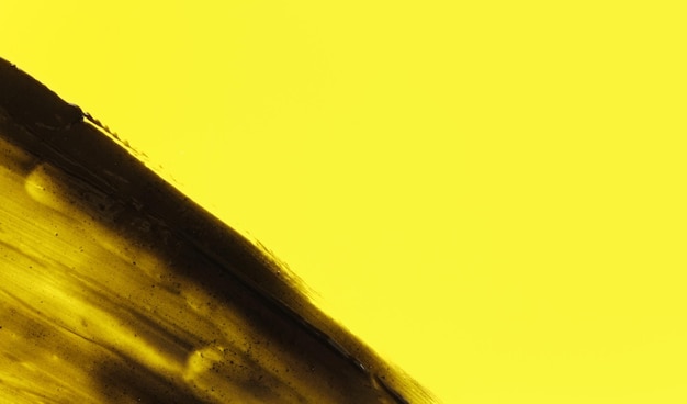Manchas pretas abstratas (pasta de dente de carvão vegetal) em fundo amarelo, espaço para o lado direito do texto
