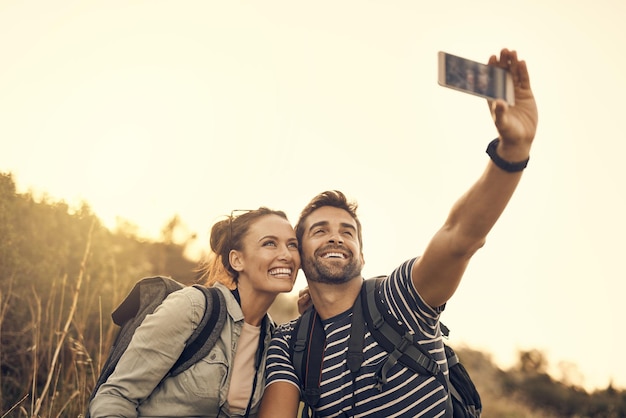 Manche Verabredungen sind einfach die Batterieleistung wert Aufnahme eines glücklichen Paares, das während einer Wanderung ein Selfie macht
