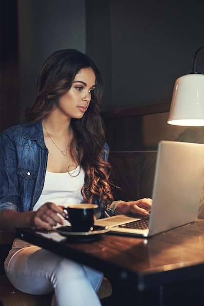 Manchmal muss man einfach aus dem Büro raus Aufnahme einer entspannten jungen Frau, die ihren Laptop in einem Café benutzt