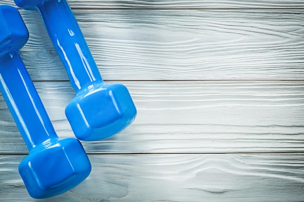 Mancuernas azules en el concepto de entrenamiento deportivo del espacio de copia del tablero de madera.