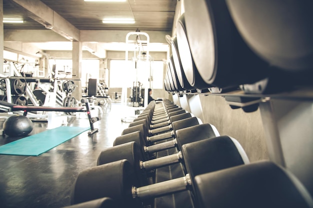 Las mancuernas están en los estantes del gimnasio. Moderno interior de gimnasio con equipamiento. Material deportivo en el gimnasio.