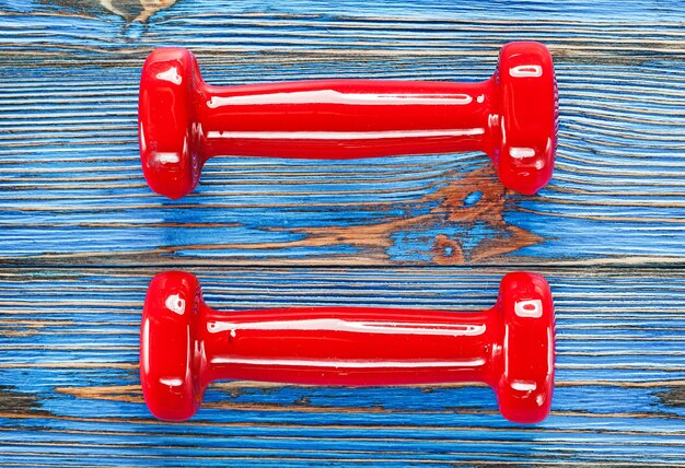 Mancuernas de fitness rojo sobre tablero de madera vintage