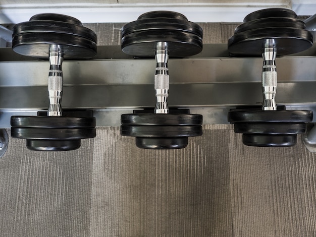 Foto mancuernas a la izquierda en los bastidores en el gimnasio.