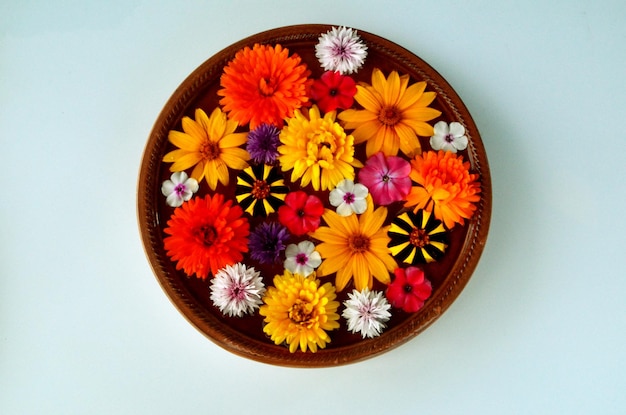Mandala de flores multicolores flotando sobre un plato de agua hecho de flores frescas.