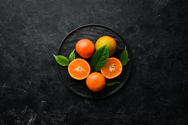 Foto mandarim em um fundo de pedra preta frutas cítricas vista superior espaço livre para o seu texto