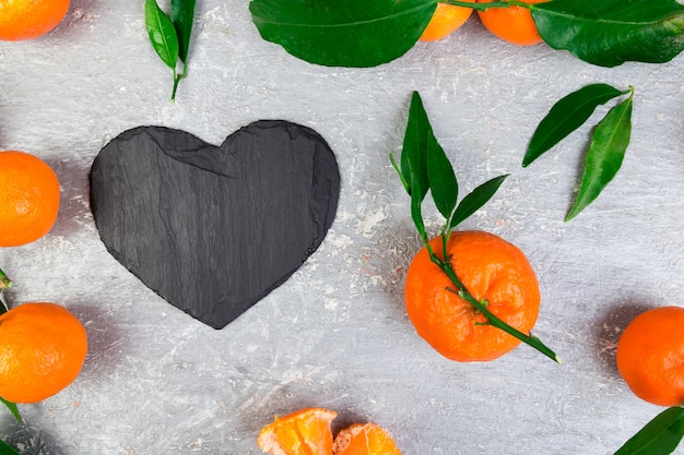 Mandarina alrededor con pizarra negra en forma de corazón.