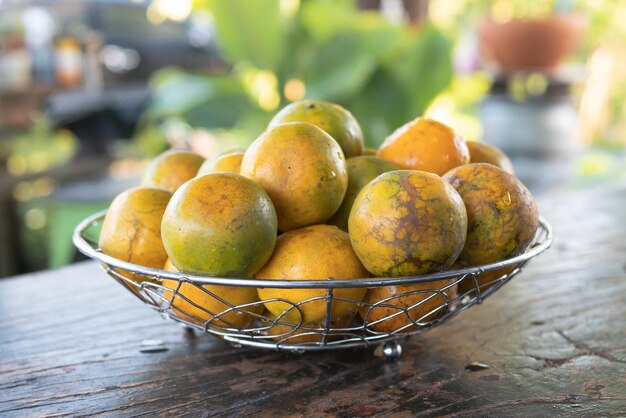 Mandarina en una canasta de metal plateado en la mesa