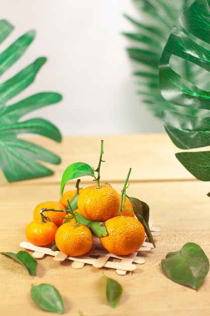 Mandarina fresca con hojas de madera sobre fondo blanco.