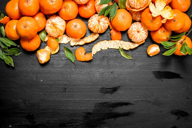 Foto mandarina fresca con hojas. en la pizarra negra.