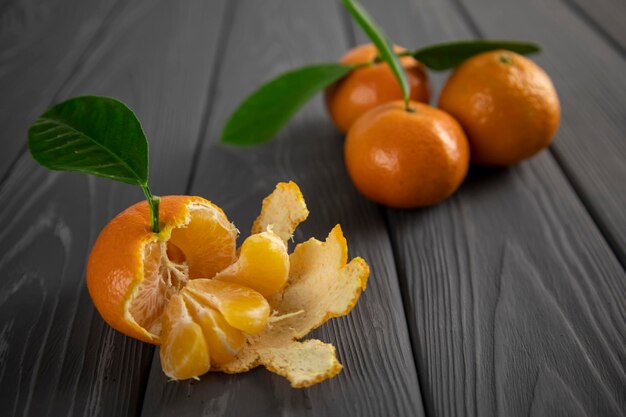 Mandarina con hoja sobre una mesa de madera. Fondo borroso.