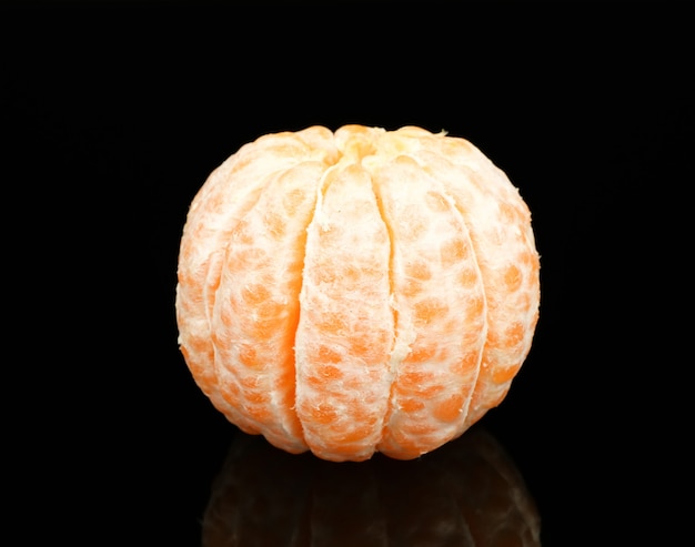 Mandarina jugosa pelada sobre fondo negro
