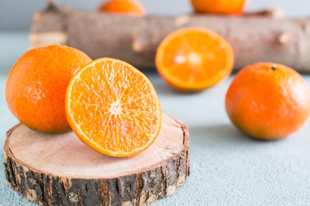 Mandarina madura cortada por la mitad en un corte de sierra de árbol y mandarinas cerca sobre un fondo azul. Frutas ecológicas. De cerca