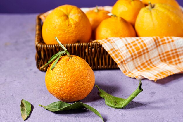 Mandarina madura fresca na cesta perto de fundo roxo