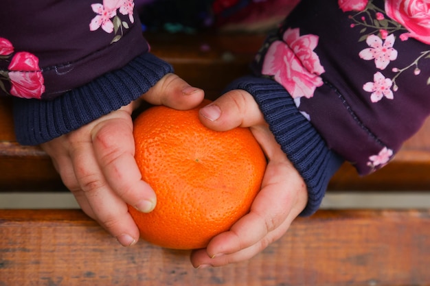 Mandarina en manos de un niño en el parque photo
