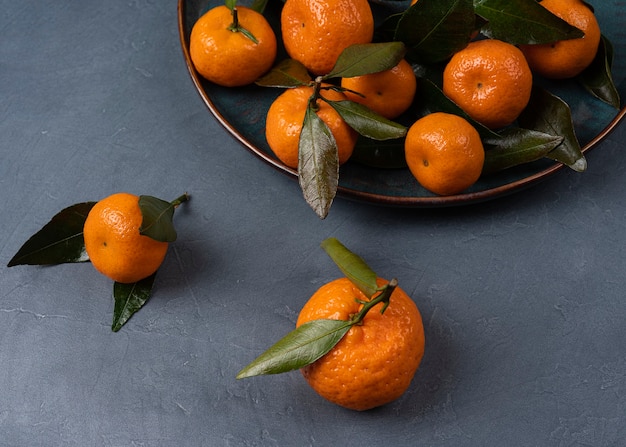 Mandarina naranja madura en un plato sobre un fondo gris macro