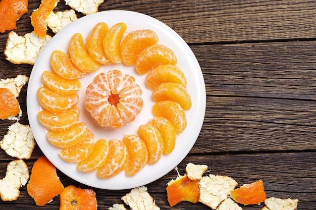 Mandarina pelada y corteza de mesa de madera antigua